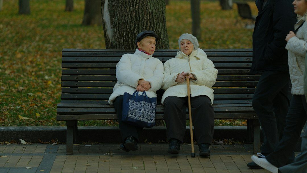 Two elderly friends laughing together outdoors in a park